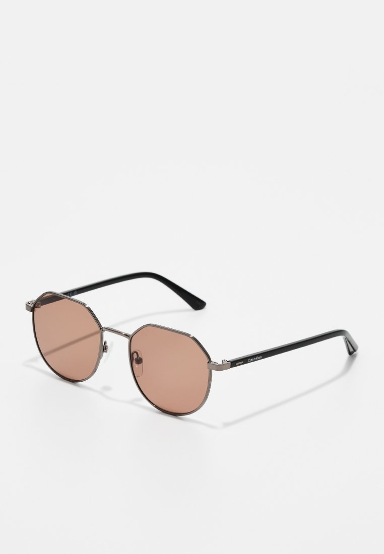 Occhiali da sole con telaio metallico, lenti ottagonali color marrone e bracci neri. Presentano dettagli argentati sul telaio per un tocco in più.