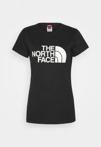 Svart bomullströja med kort ärm, med en framträdande vit logotyp som säger "THE NORTH FACE" och en böljande designdetalj.