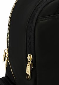 Czarny plecak z złotym zamkiem błyskawicznym i metalowym uchwytem, wykonany z fakturowanej tkaniny. Projekt zawiera wiele przegród.
