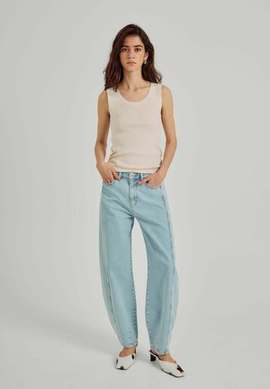 Beige ribbet tanktop, lyseblå vide jeans og hvide mules med sorte akcenter. Enkel, afslappet påklædning med en løs pasform.