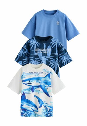 Trois t-shirts à manches courtes : bleu clair, marine avec des palmiers, et blanc avec des requins bleus. En coton, avec des designs graphiques et des textes.