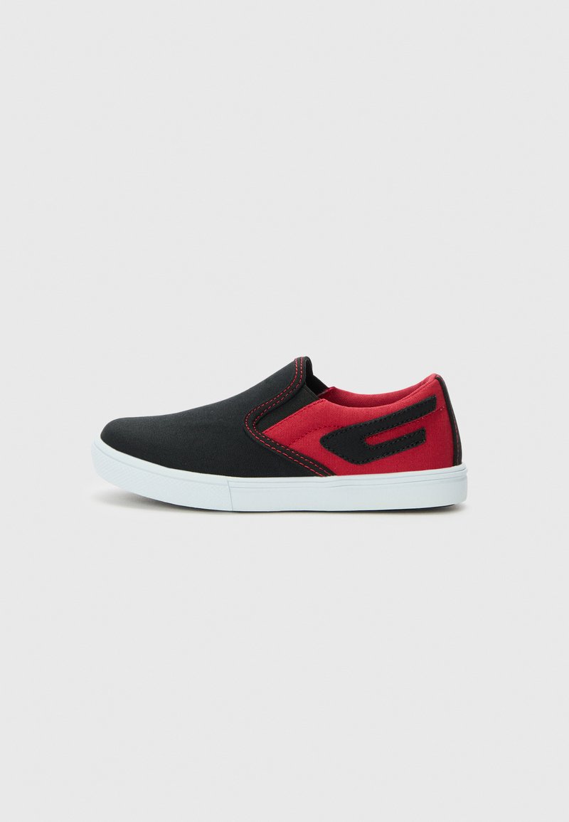 Zapatilla slip-on en negro y rojo con suela blanca, costuras rojas y un parche decorativo negro en la zona del talón rojo, presentada sobre un fondo liso.