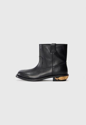 Mustvalge nahast ankle-botid sujuva pinnaga, ümarate varvastega ja kuldse aksendiga vaala motiiviga kontsapool. Minimalistlik disain.