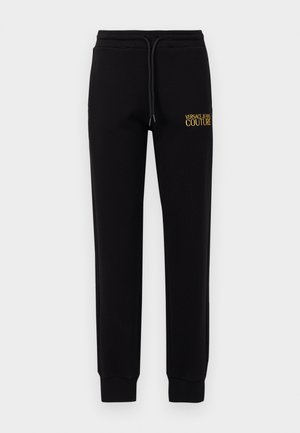 Sorte joggebukser laget av myk stoff, med elastisk midjebånd og snor, samt gult brodert "VERSACE JEANS COUTURE"-logo.