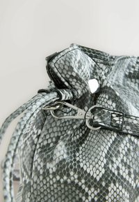 Geantă texturată din piele de șarpe falsă în nuanțe de gri, cu accente negre. Dispune de un închizător de tip clips argintiu și de o mânere împletită.