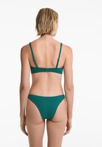 Top de bikini teal cu dungi, cu baretă ajustabilă și închidere cu cârlig, asortat cu chiloți de bikini cu croi jos.