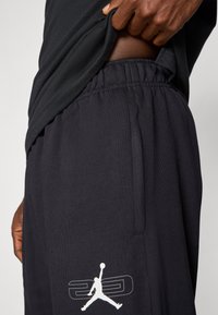 Čierne športové šortky vyrobené z jemného materiálu, s elastickým pásom a bočnými vreckami. Výrazné biele logo Jumpman na ľavom stehne.