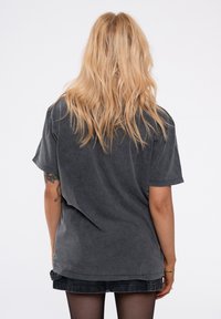 Dark gray oversized t-shirt with short sleeves and a vintage wash. Soft cotton texture, relaxed fit, and a rounded hem. No visible graphics.