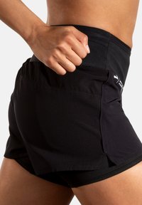 Shorts de course noirs avec une finition texturée, dotés d'une poche latérale et d'un design à ourlet fendu pour une mobilité accrue pendant l'activité.