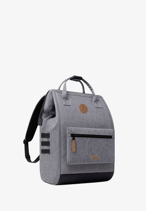 Gray rectangular backpack with black bottom, front zip pocket, dual top handles, padded shoulder straps, and a circular logo patch.