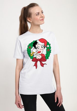 Hvid T-shirt med en tegneseriefigur iført en rød nissehue, omkranset af en julestjerne og en rød sløjfe. Materialet er bomuld.