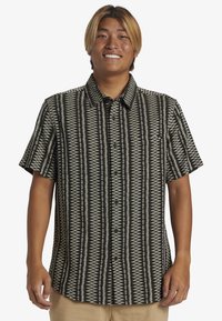 Camisa de manga corta en negro y crema con un patrón geométrico, que cuenta con un cierre de botones en el frente y un cuello clásico. Material de algodón.