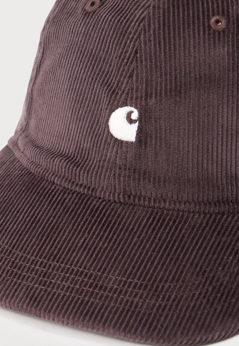 Cappellino da baseball in velluto a coste di colore marrone scuro con un piccolo logo bianco ricamato sul pannello frontale.