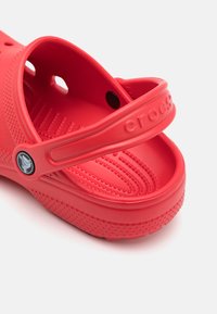 Rode Crocs-sandalen met een gesloten teen, afvoeropeningen en een gestructureerde binnenzool. Gemaakt van lichtgewicht rubber met een verstelbare hielband.
