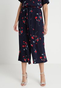 Pantaloni culotte blu navy con motivo floreale in rosso e verde, vita annodata, vestibilità ampia e lunghezza al polpaccio, realizzati in tessuto leggero.