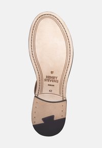 Sohle aus hellfarbigem Leder mit dunklen Gummibereichen, versehen mit geprägtem Branding "HENRY STEVENS" und einer Größenangabe "42."