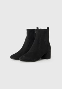 Stivaletti neri in suede con tacco a blocco e cerniere laterali, esposti su uno sfondo grigio neutro.