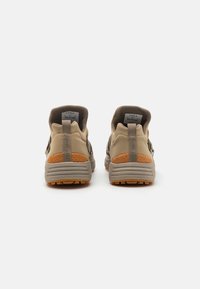 Beige sport schoenen met getextureerde rubberen zolen, gewatteerde kraag en een contrasterende oranje accent op de hiel, met een lage bovenkant.
