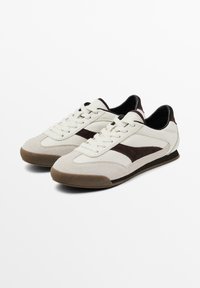 Sneakers di colore crema chiaro con accenti in suede marrone, design con lacci, parte anteriore testurizzata e suola in gomma per una migliore aderenza. Profilo elegante e dettagli minimi.