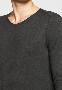 Dark gray long-sleeve t-shirt made of soft fabric. Features a crew neckline and visible stitching along the shoulders. No patterns or accents.
