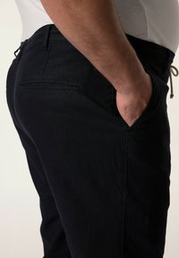 Pantaloni blu scuro realizzati in tessuto morbido, con taglio dritto, tasche laterali e una tasca posteriore con un dettaglio di cucitura discreto.