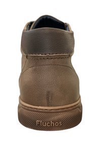 Bruine leren enkellaarsjes met een gestructureerde afwerking, rubberen zool en gestikte details. Bevat een logo "Fluchos" aan de zijkant.