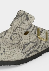 Παπούτσι τύπου slip-on με γκρι και μαύρο σχέδιο από δέρμα φιδιού, χρυσό κουμπωτό στο πλάι και μαύρη υφή στη σόλα.