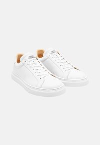 Weiße Leder-Sneaker mit glatter Oberfläche, runder Zehenpartie, Schnürdesign und tanfarbenem Innenraum. Mit einem dezenten Logo auf der Zunge.