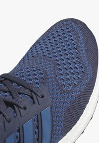 Sapatilha atlética azul com parte superior em malha texturizada, área de atilhos reforçada e entressola branca. Apresenta tons contrastantes de azul no design.