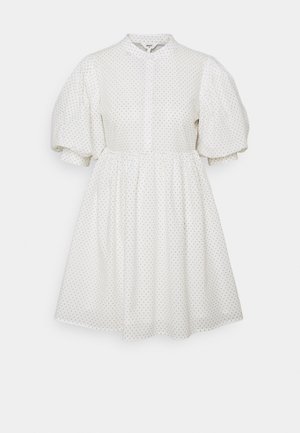Biała sukienka do kolan z bufkami przy krótkich rękawach, małymi czarnymi kropkami, wysokim kołnierzem i zapinaniem na guziki z przodu.