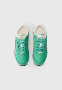 Sapatilhas de tecido verde com materiais de malha e camurça, com atacadores turquesa, pormenores em rosa e um interior almofadado. Logótipo da Reebok visível.
