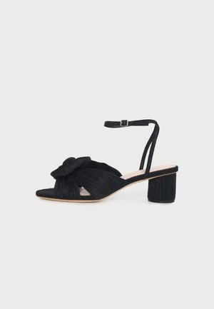 Sandale noire à bout ouvert avec talon bloc bas, nœud en tissu texturé à l'avant et fine bride de cheville avec fermeture à boucle.