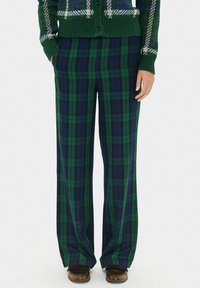 Pantaloni a quadri in verde scuro e navy, con gamba ampia e una morbida trama. Il motivo presenta quadrati e linee alternate.