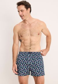 Marina kalsonger med ett flerfärgat mönster av fåglar och löv, tillverkade av mjukt tyg med ett elastiskt midjeband.