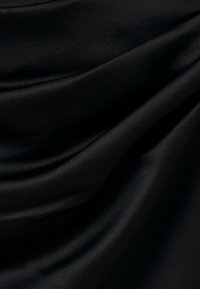 Tissu en satin noir lisse avec des plis doux et un éclat subtil sous une lumière douce.