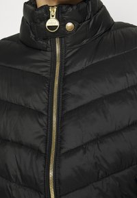 Gepolsterte schwarze Daunenjacke mit hohem Kragen, goldener Reißverschluss und Druckknopfverschluss. Verfügt über horizontale Chevron-Nähte für zusätzliche Struktur.