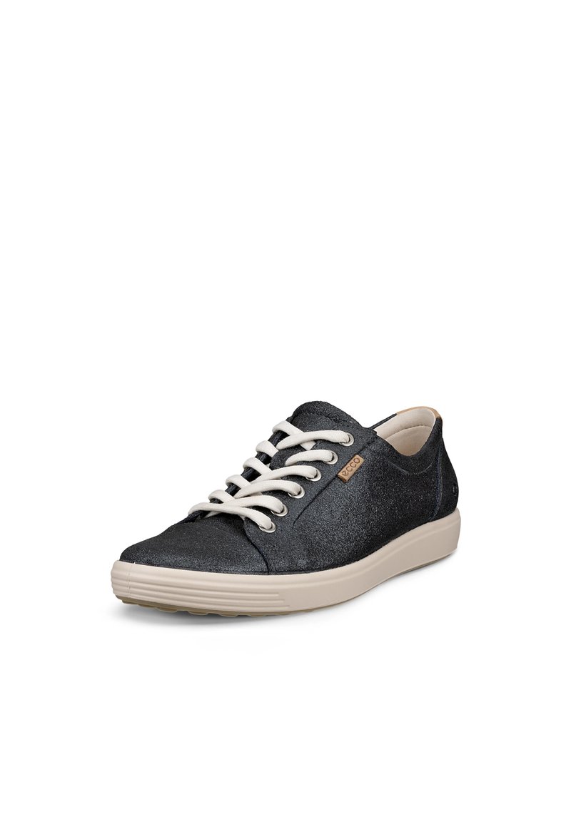 Zapatillas negras brillantes con cordones crema, punta redonda, suela de goma beige y un pequeño logo en el lateral. Acabado de material suave.