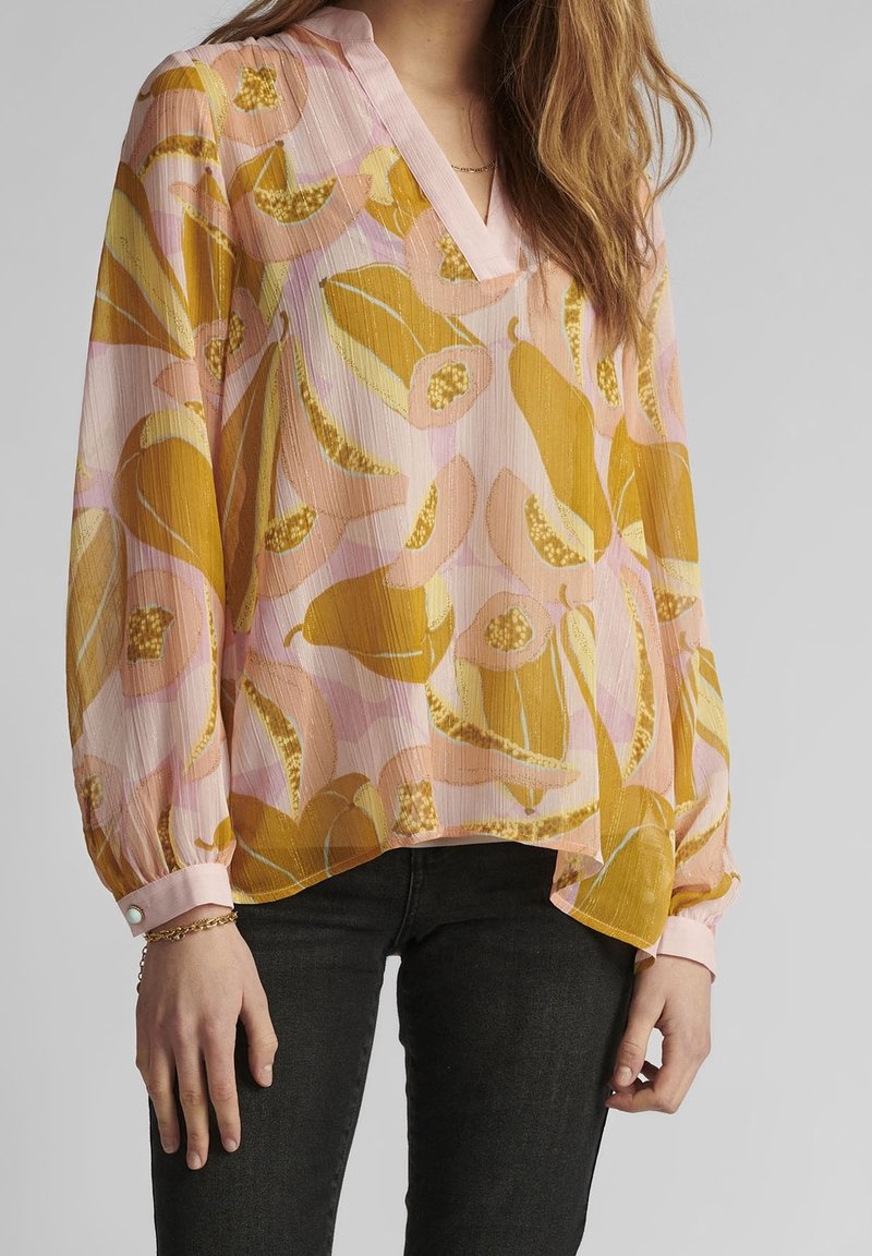 Genomskinlig, lätt blus i rosa och gult med blommigt mönster. Har V-ringning, långa ärmar och rosa knäppte manschetter. Texturerad tyg.