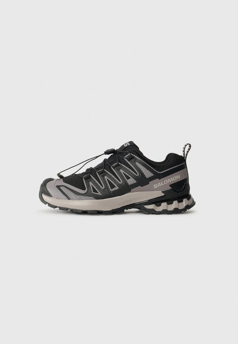 Chaussure de trail running Salomon noire et grise avec semelle robuste, système de laçage rapide et languette au talon sur fond clair.