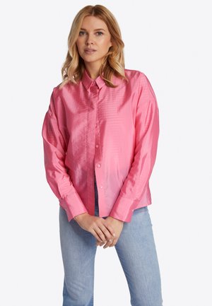 Roze satijnen overhemd met knopen, klassiek kraag, lange mouwen en een gladde textuur, gecombineerd met lichtblauwe jeans.