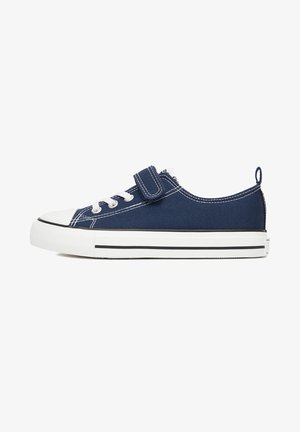 Scarpa da ginnastica in tela blu navy con suola in gomma bianca, lacci bianchi, cinturino in Velcro e linguetta sul tallone, mostrata di profilo laterale.