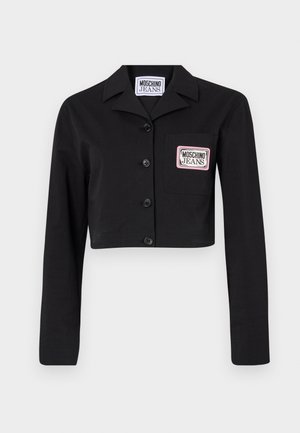 Jaqueta curta preta feita de um tecido suave, com fecho de botão na parte da frente, colarinho pontudo e um bolso na chest com um emblema branco e rosa.
