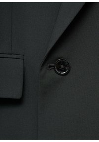 Black blazer fabric with smooth texture and structured lapel. Features a single black button with a carved floral design and a side pocket.