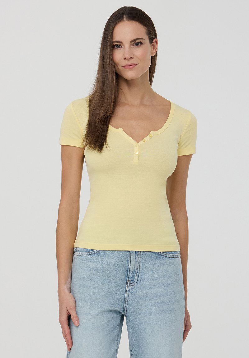 T-shirt giallo a maniche corte henley realizzato in cotone morbido, con scollo a barca, patta con tre bottoni e design aderente.