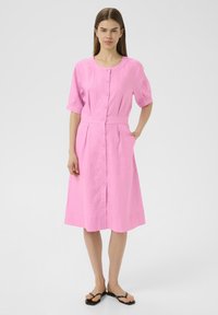 Abito button-up in lino rosa con maniche corte, vita aderente e gonna svasata. Presenta un colletto rotondo e una texture sottile.