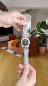 Hõbedane roostevabast terasest kell musta dialiga, seotud käevõruga ja tekstureeritud äärisega. Kellakäed on lihtsad, tundide ja minutite näidud on selged.