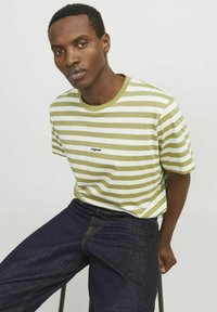Grøn- og hvidstribet T-shirt med rund hals og "originals" logo, parret med mørke denimjeans. Glat stof med en afslappet pasform.