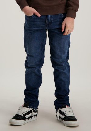 Blauwe spijkerbroek, rechte pasvorm, middelhoge taille, lichte slijtage. Draag met zwart-witte sneakers, met vetersluiting en rubberen zolen.