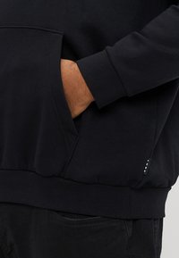 Černá mikina s kapucí z měkké bavlněné směsi, s klokaní kapsou, žebrovanými manžetami a lemem a jemnou značkovou nášivkou v pase.