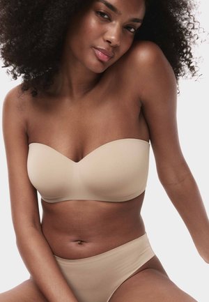 Beige stropløs bh med blød tekstur og sømløst design, kombineret med matchende højtaljede trusser med en glat finish.